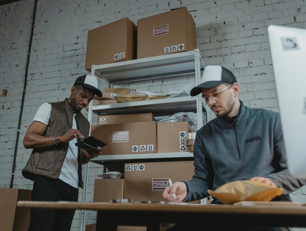 Two warehouse employees organizing and packing parcels for delivery in a modern indoor setting.